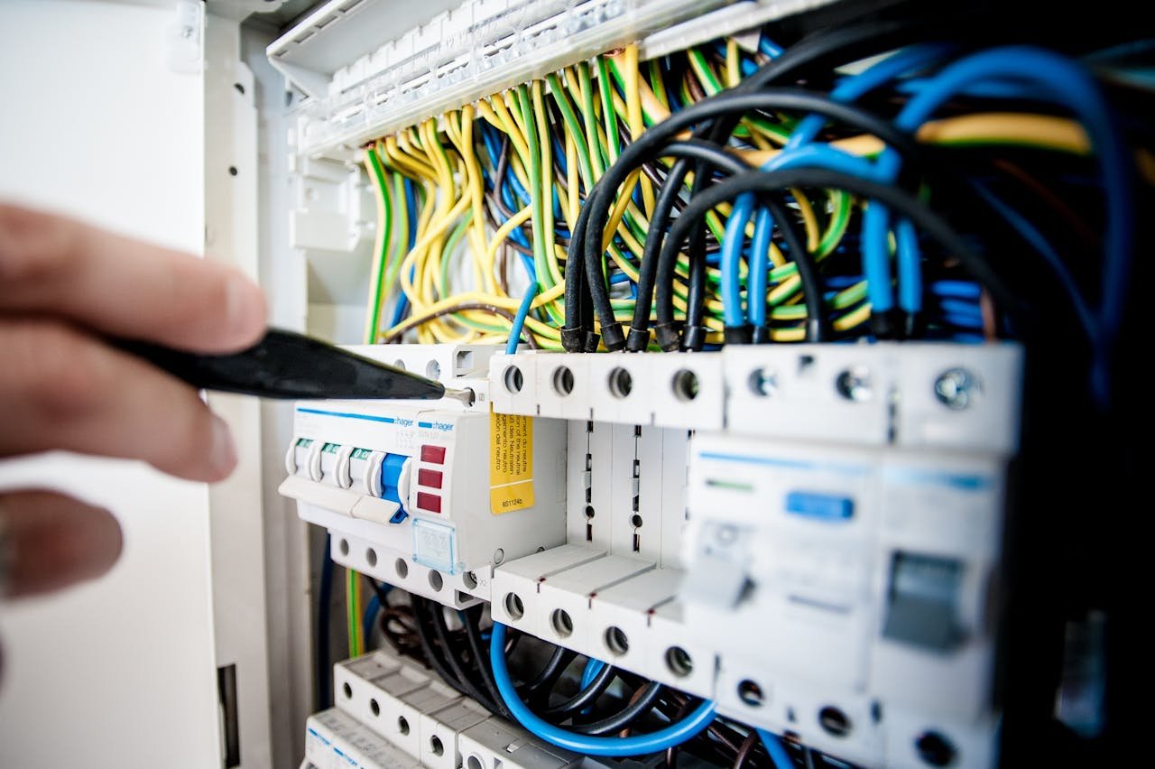 Services Hand of electrician working on a circuit breaker panel with colorful wires, ensuring safe electrical connections.